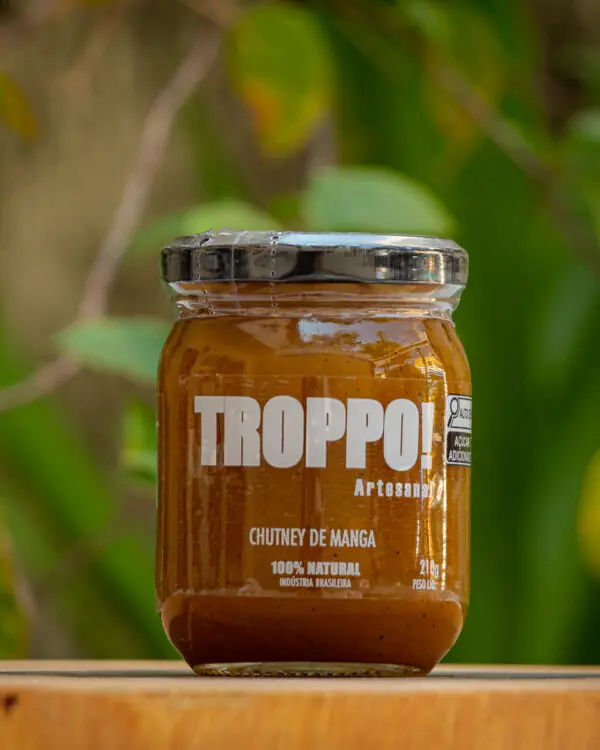 Pote de vidro de Chutney de Manga Troppo Artesanal 210g sobre madeira com fundo verde
