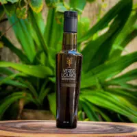 Azeite Extra Virgem Blend Azeite Extra Virgem Blend Verde Louro 250ml Edição Limitada em garrafa preta e dourada sobre tronco rústico