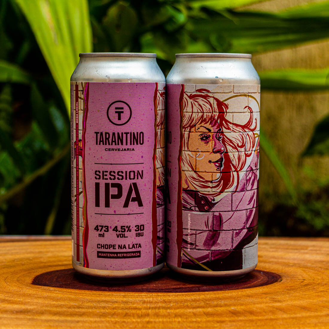 Duas latas da Cerveja Session IPA da Cervejaria Tarantino, com seu rótulo artístico e urbano em destaque sobre uma base de madeira.