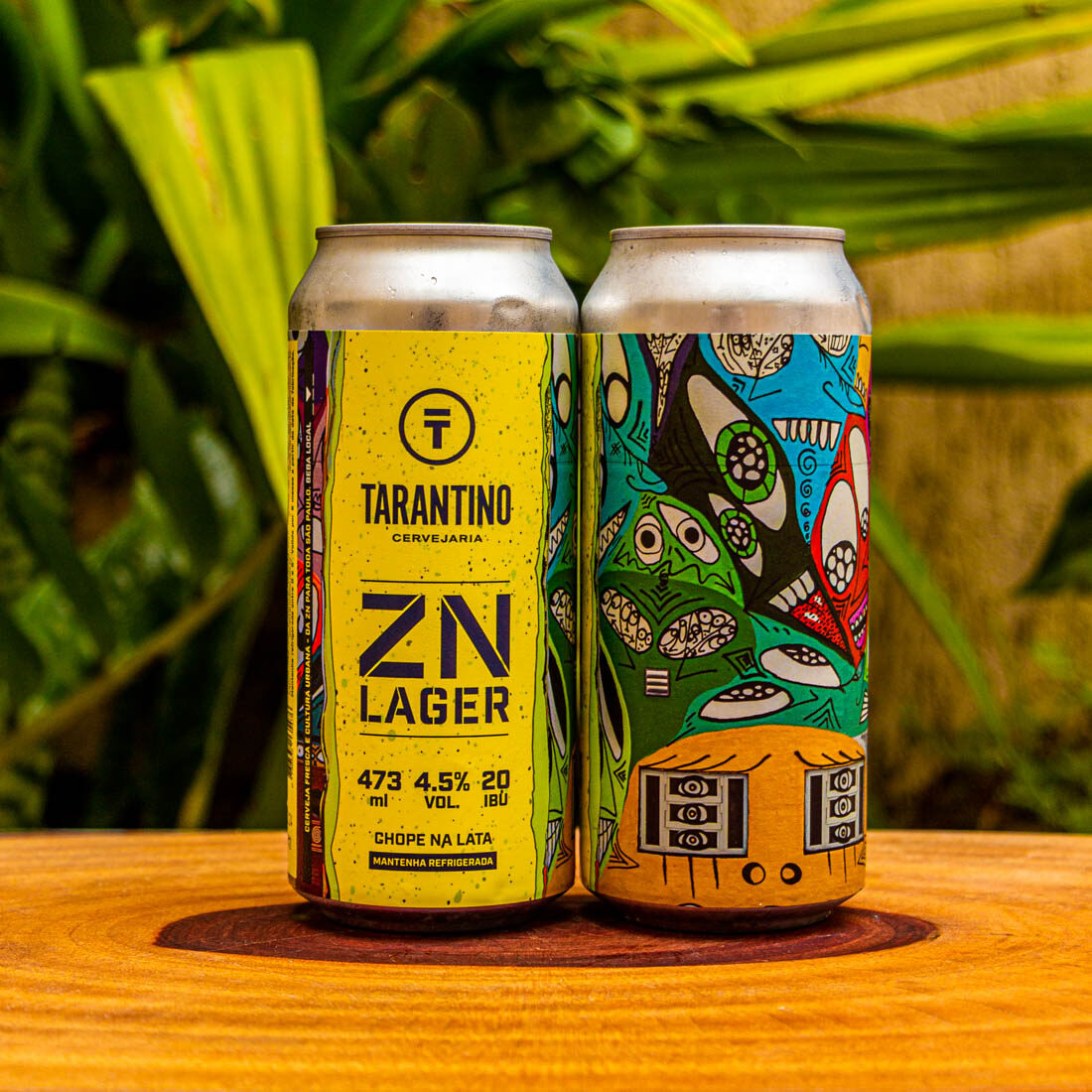Duas latas da cerveja artesanal ZN Lager da Cervejaria Tarantino, com rótulo amarelo vibrante e arte urbana colorida na lateral.