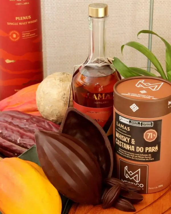 Ovo de Páscoa Mestiço 71% amargo com Whisky Mineiro Plenus e Castanha do Pará aberto junto a garrafa de whisky.