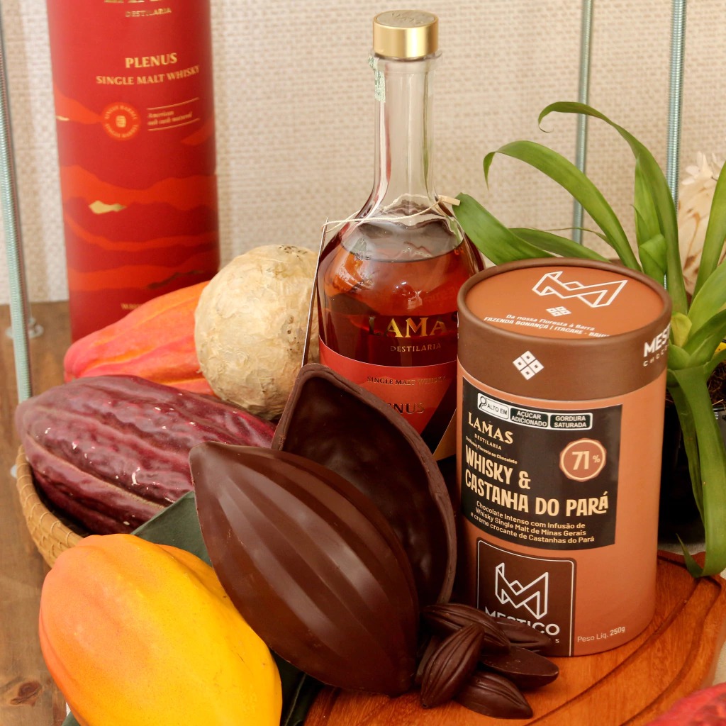 Ovo de Páscoa Mestiço 71% amargo com Whisky Mineiro Plenus e Castanha do Pará aberto junto a garrafa de whisky.