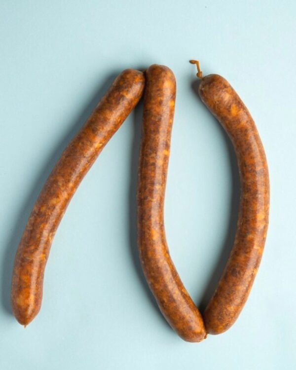 Linguiça Merguez bovina picante da FA Defumados sobre tábua de madeira rústica.