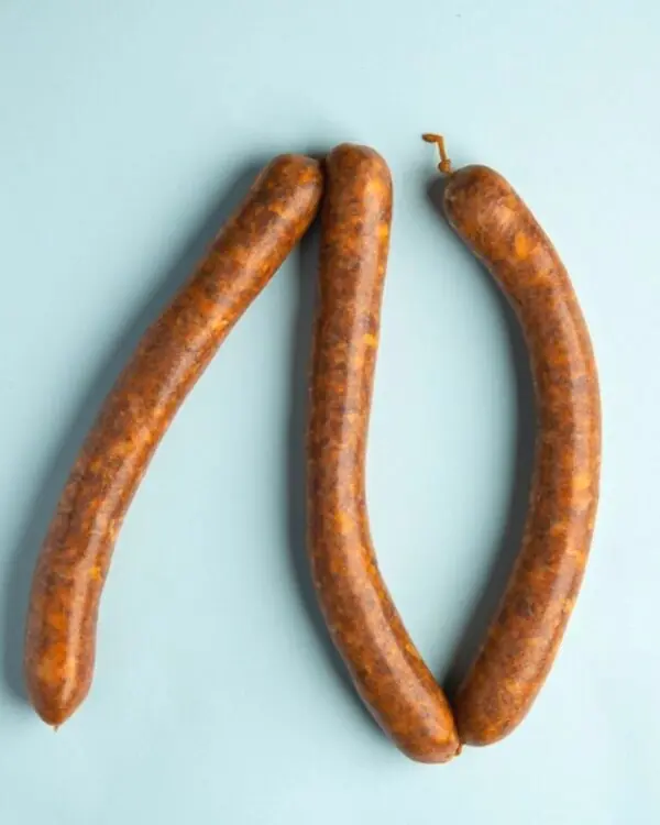 Linguiça Merguez bovina picante da FA Defumados sobre tábua de madeira rústica.