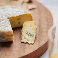 Queijo Azul do Bofete servido na tábua, revelando sua textura amanteigada extra macia com intensos veios azuis. Queijo Azul do Bofete servido na tábua, revelando sua textura amanteigada extra macia com intensos veios azuis.