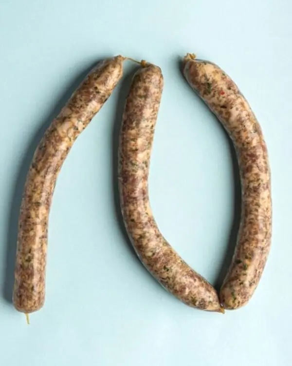 Linguiça do Sertão artesanal com pimenta biquinho da FA Defumados sobre tábua rústica.