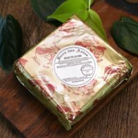Queijo Taleggio Serra das Antas em embalagem dourada premium sobre tábua de madeira rústica e folhas verdes. Queijo Taleggio Serra das Antas em embalagem dourada premium sobre tábua de madeira rústica e folhas verdes.
