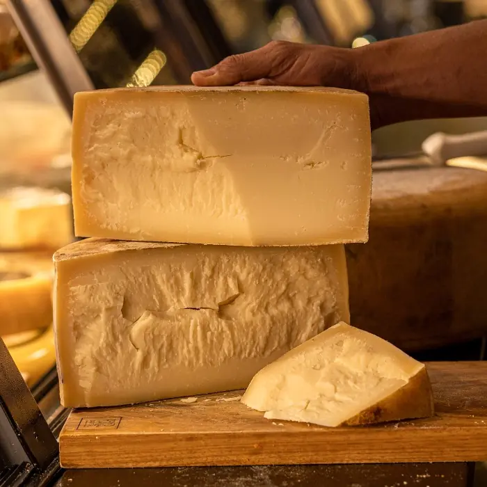 Peças de Queijo Tulha Fazenda Atalaia abertas em uma tábua, destacando a textura granular e a cor amarelo-alaranjada característica da maturação prolongada.