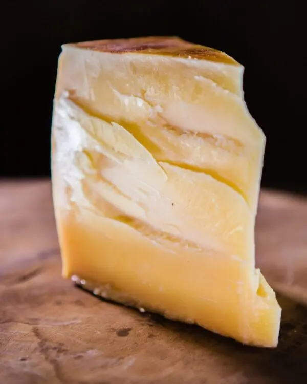 Cunha do queijo duro Tulha Fazenda Atalaia exibindo ranhuras de cristais de tirosina na massa clara. Cunha do queijo duro Tulha Fazenda Atalaia exibindo ranhuras de cristais de tirosina na massa clara.