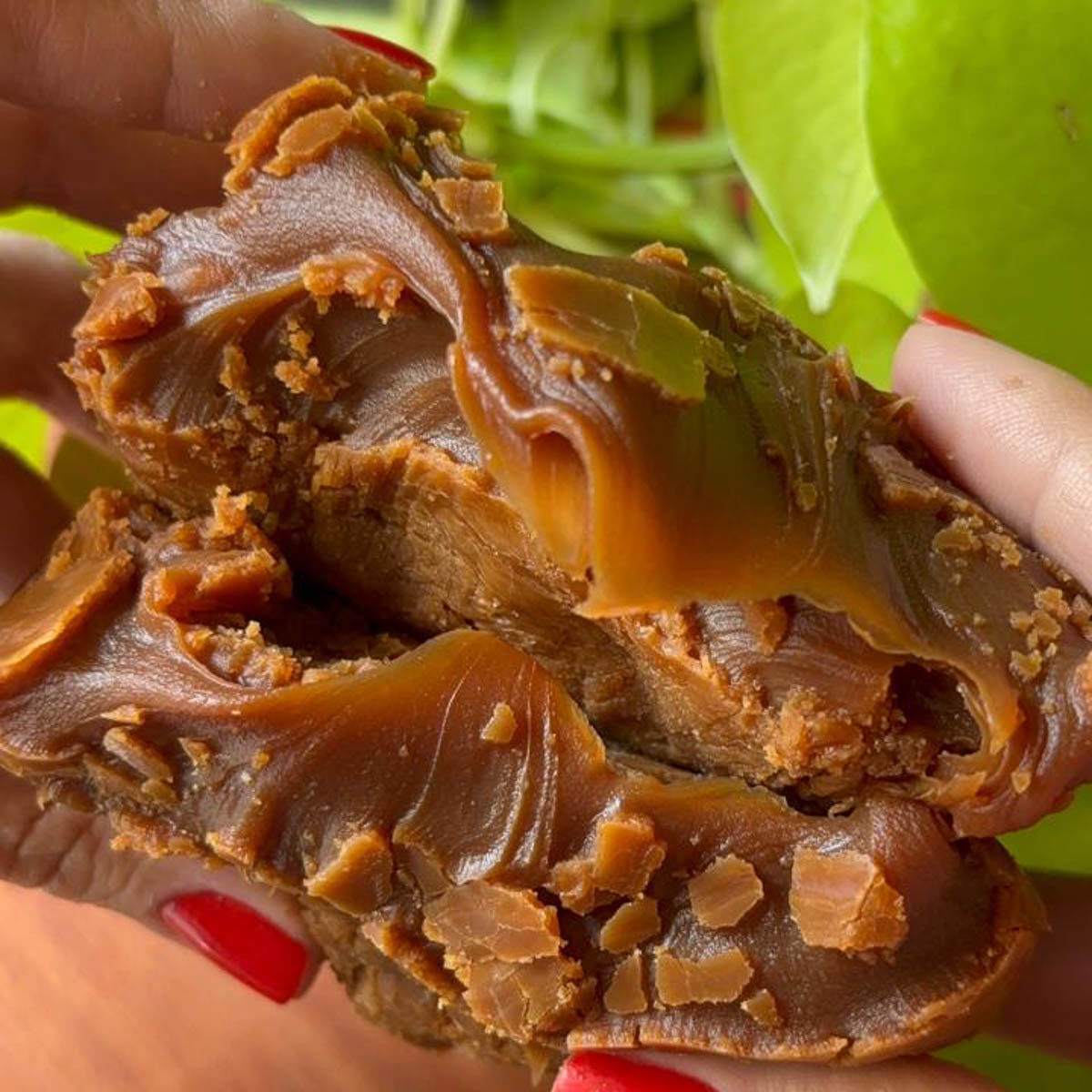 Extremo close do doce de leite doce denso, esticando um recheio caramelo úmido e brilhante feito pra derreter na boca.