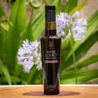 Azeite Extra Virgem Frantoio 250ml da Verde Louro em garrafa de vidro escuro sobre base de madeira com folhagens verdes ao fundo