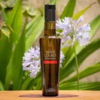 Azeite Extra Virgem Arbosana Verde Louro de 250ml, faixa vermelha da safra atualizada sobre placa de madeira e folhas verdes