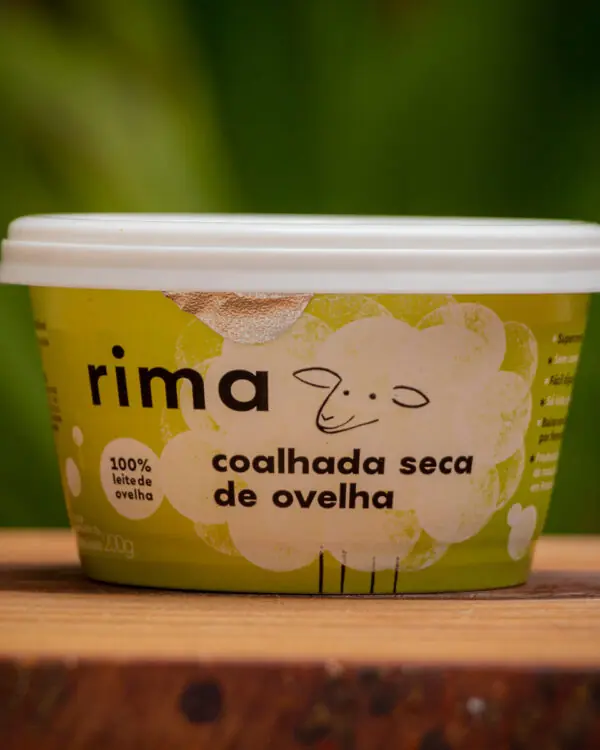 Coalhada Seca de Ovelha Rima 200g sobre tábua rústica de madeira em cenário natural.