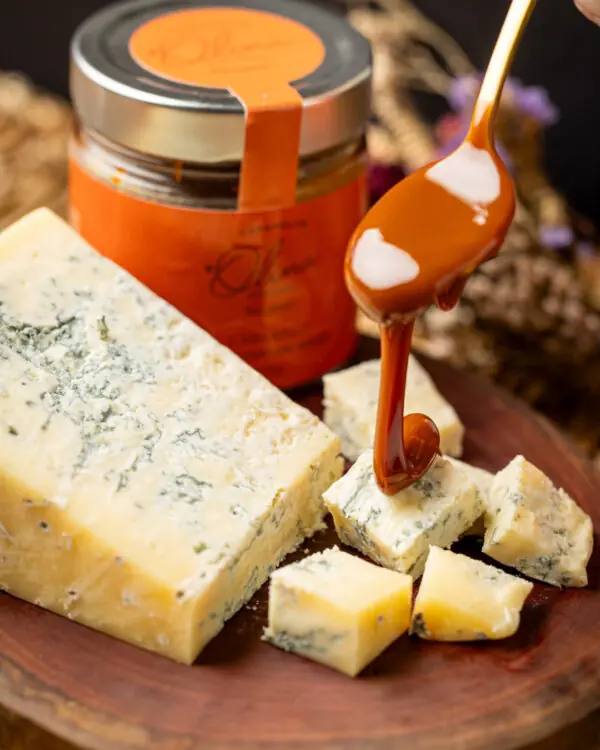 Calda de caramelo de chocolate e laranja sendo despejada sobre queijo gorgonzola em tábua rústica. Calda de caramelo de chocolate e laranja sendo despejada sobre queijo gorgonzola em tábua rústica.