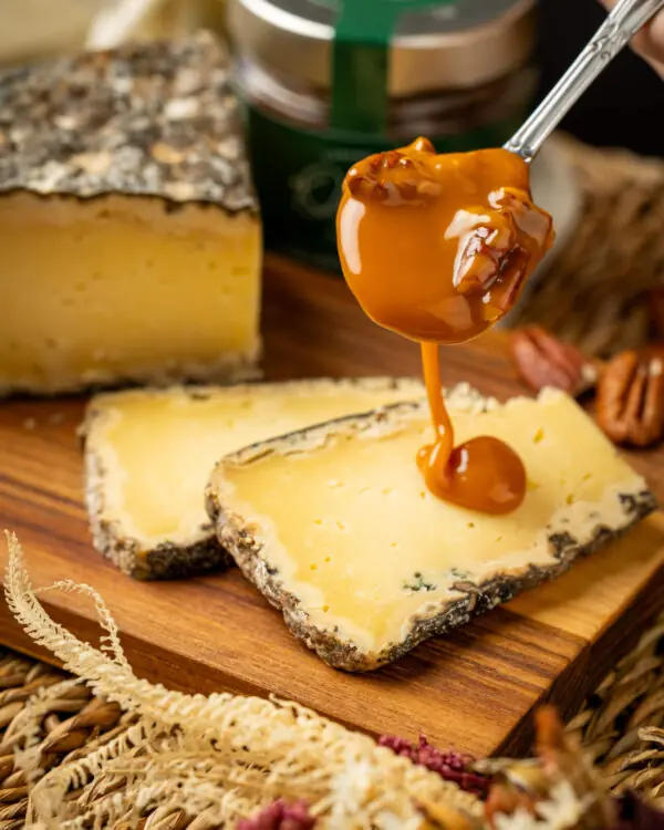 inâmica da Calda de caramelo rústico e doce amadeirada despejada graciosamente por cima das fatias amarelas pontilhadas do puro queijo curado, servido acima da base tabulada de carne natural rústica. inâmica da Calda de caramelo rústico e doce amadeirada despejada graciosamente por cima das fatias amarelas pontilhadas do puro queijo curado, servido acima da base tabulada de carne natural rústica.