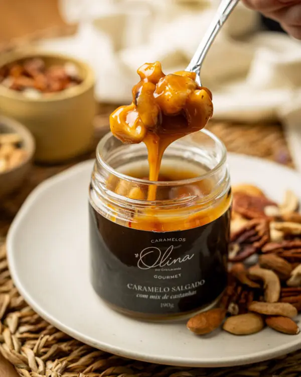 Colherada farta de caramelo salgado brilhante e espesso com castanhas pecãs enormes sobre o pote de vidro da Olina. Colherada farta de caramelo salgado brilhante e espesso com castanhas pecãs enormes sobre o pote de vidro da Olina.