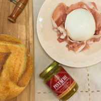 Pesto de Pistache Origens Grechi com burrata sobre presunto cru e pão artesanal — mesa italiana
