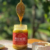 Colher retirando pesto de pistache Origens Grechi do pote mostrando textura cremosa e granulada