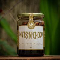 Pote de vidro do mix de castanhas com chocolate Nuts'n Choco Rutz 350g sobre mesa de madeira.