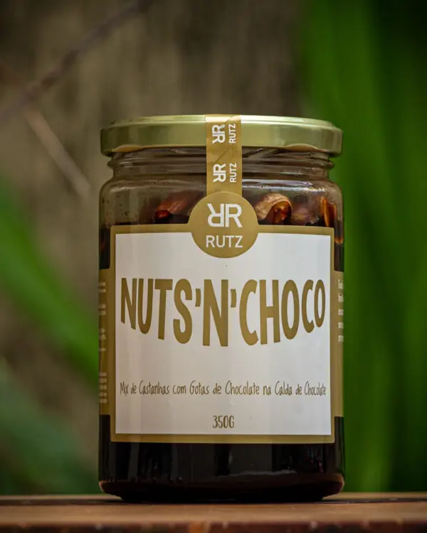 Pote de vidro do mix de castanhas com chocolate Nuts'n Choco Rutz 350g sobre mesa de madeira.
