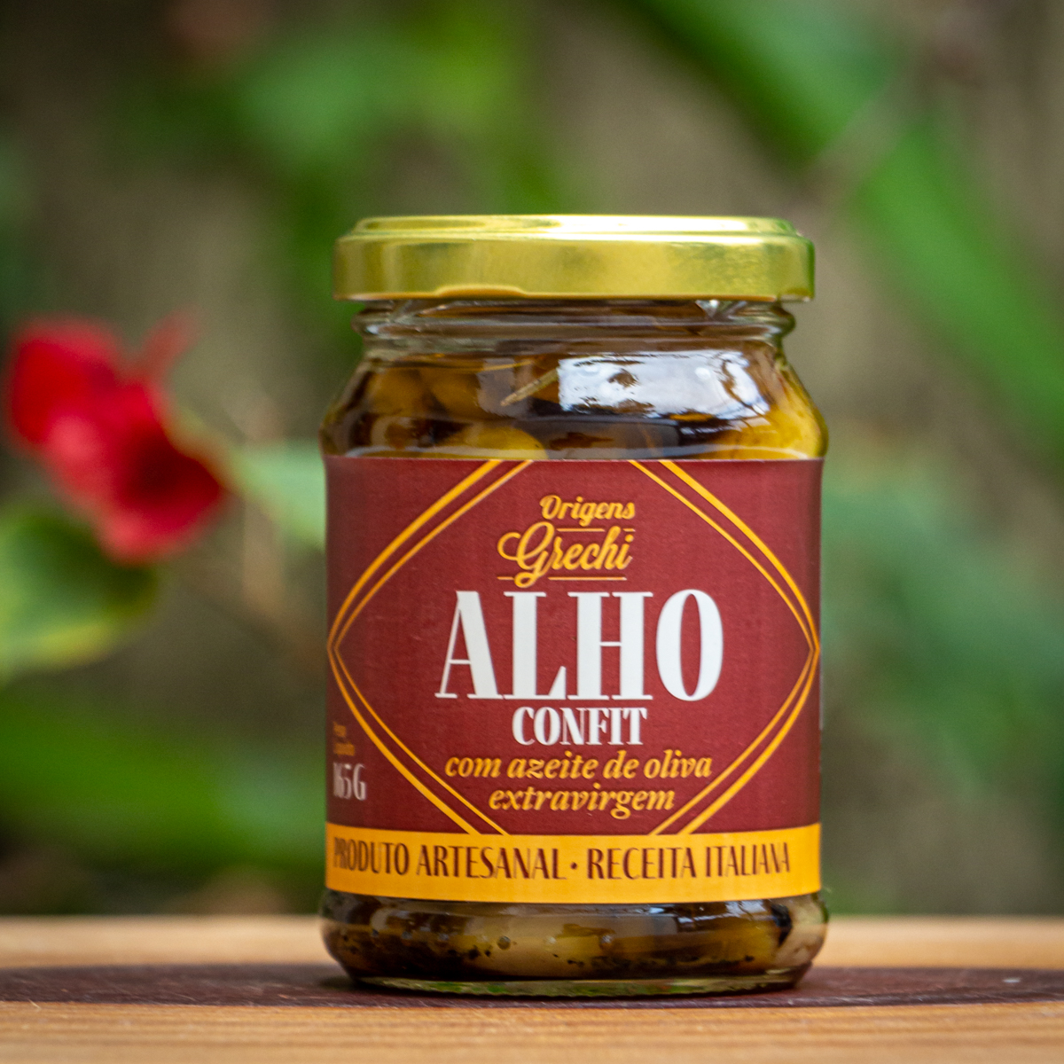 Pote de Alho Confit Origens Grechi sobre madeira rústica, destacando o alho confitado artesanal em azeite.