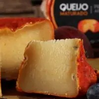 Queijo Jordão Pasta Dura cortado mostrando pasta amarelo-dourada casca urucum vermelha maturado