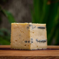 Pedaço Queijo Azul de Pardinho com veios azuis sobre tábua de madeira